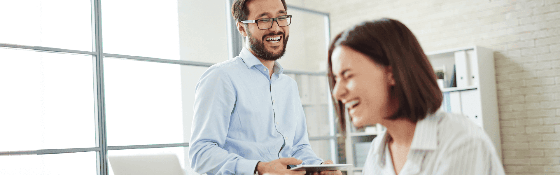 Spaß bei der Arbeit in der Steuerbranche – Lächelnde Kollegen im Büro zeigen, dass Teamgeist und ein positives Arbeitsumfeld für Motivation und Erfolg sorgen.