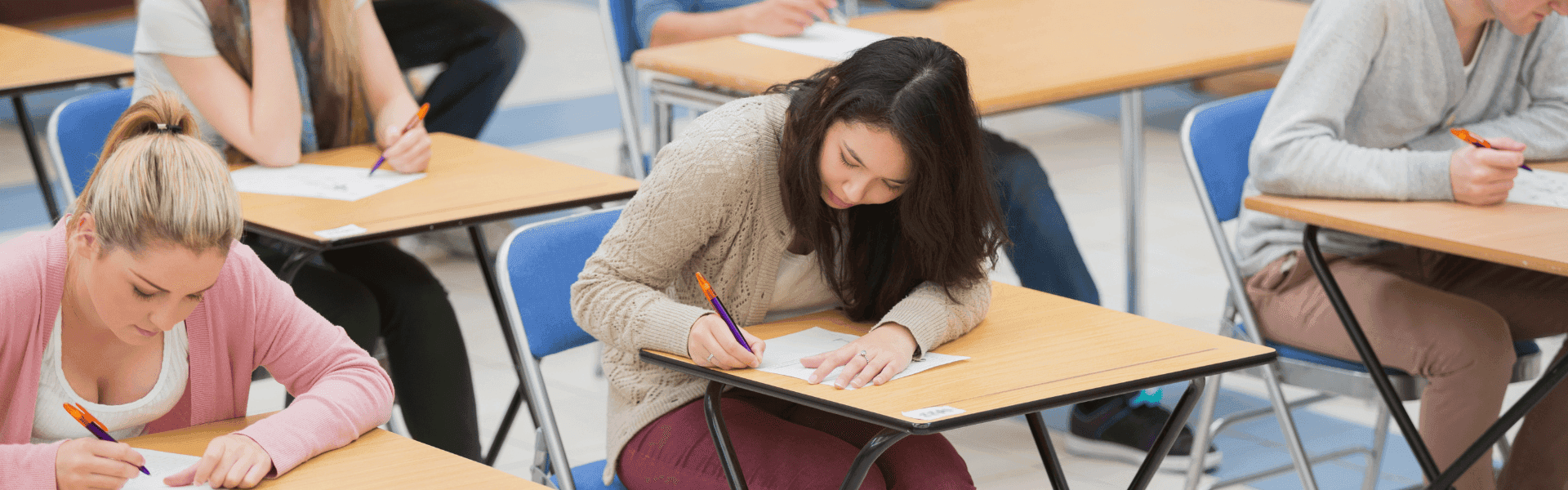 Prüflinge schreiben Examen an Tischen